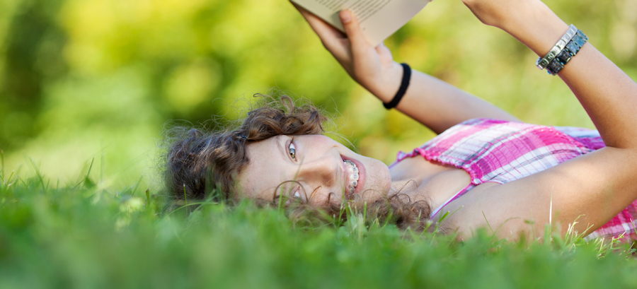 Junges Mädchen liest ein Buch auf der Wiese